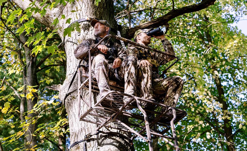 two dudes in a tree hanging out in camo